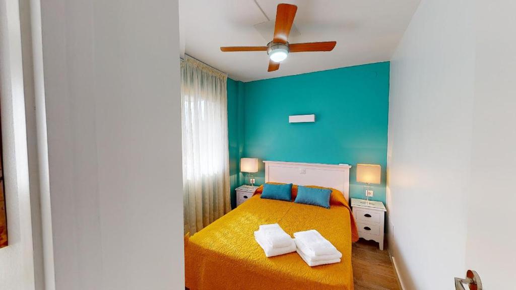 a bedroom with a yellow bed and a blue wall at Apartamentos Eldorado in Lloret de Mar
