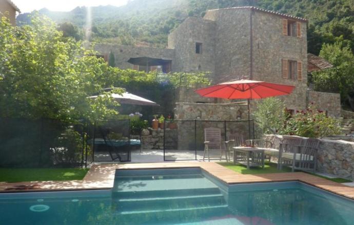 a swimming pool with a red umbrella and a table and a patio at Casa paghjola in Urtaca