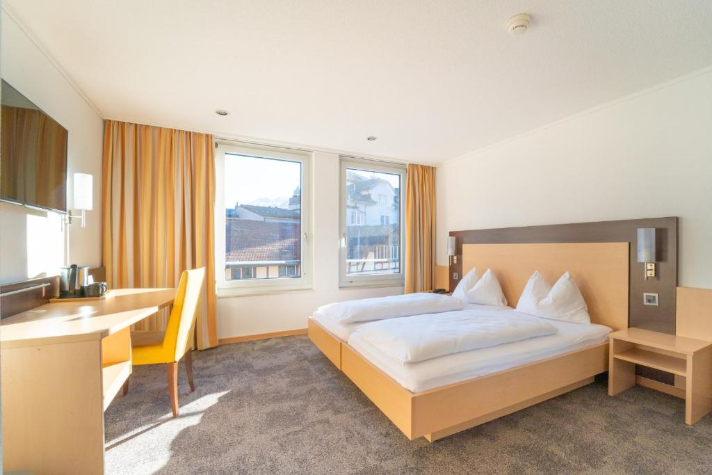 ein Hotelzimmer mit einem Bett und einem Schreibtisch in der Unterkunft The Guesthouse by The Hey Hotel in Interlaken