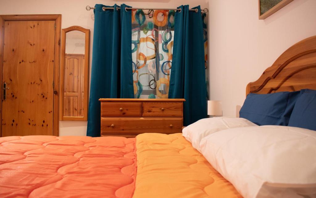 a bedroom with a bed and a dresser and blue curtains at Spacious 3 bedroom apartment in Marsascala in Marsaskala