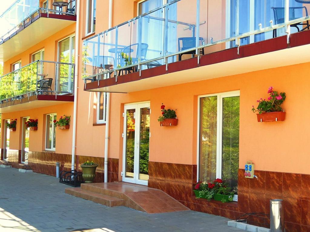 an orange building with potted plants and a balcony at Pajurio Vila in Palanga