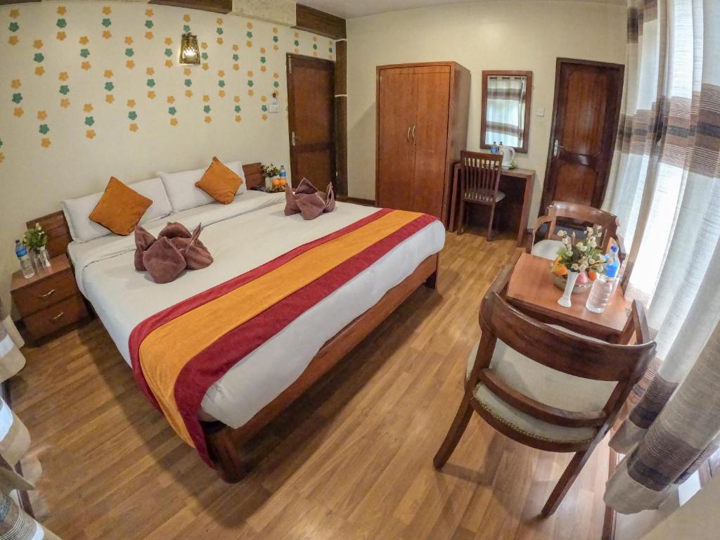 a bedroom with a large bed and a desk with a table at Royal Kings Hotel in Kathmandu