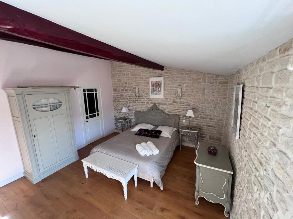 a bedroom with a bed and a brick wall at Le Puits Sainte Claire in Courçon