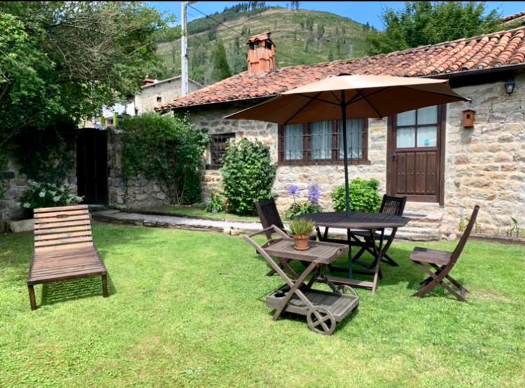 una mesa, sillas y una sombrilla en un patio en La Casita de Cuestallano, en Renedo