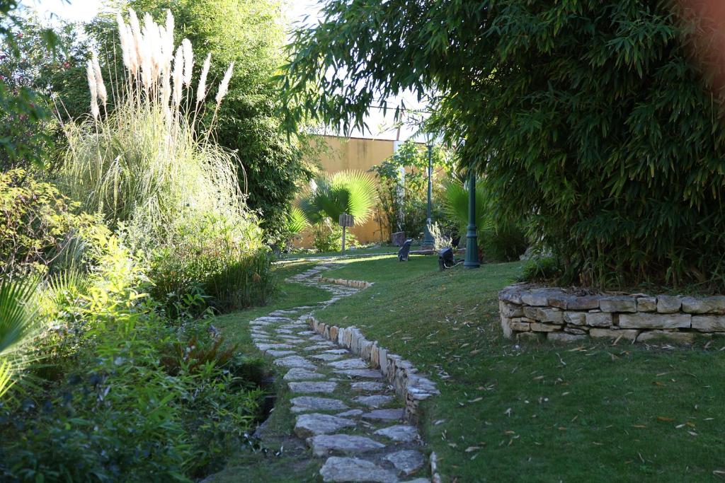 un camino de piedra en un jardín con un árbol en Quinta Lagus Resort - Casa de Campo, en Palmela