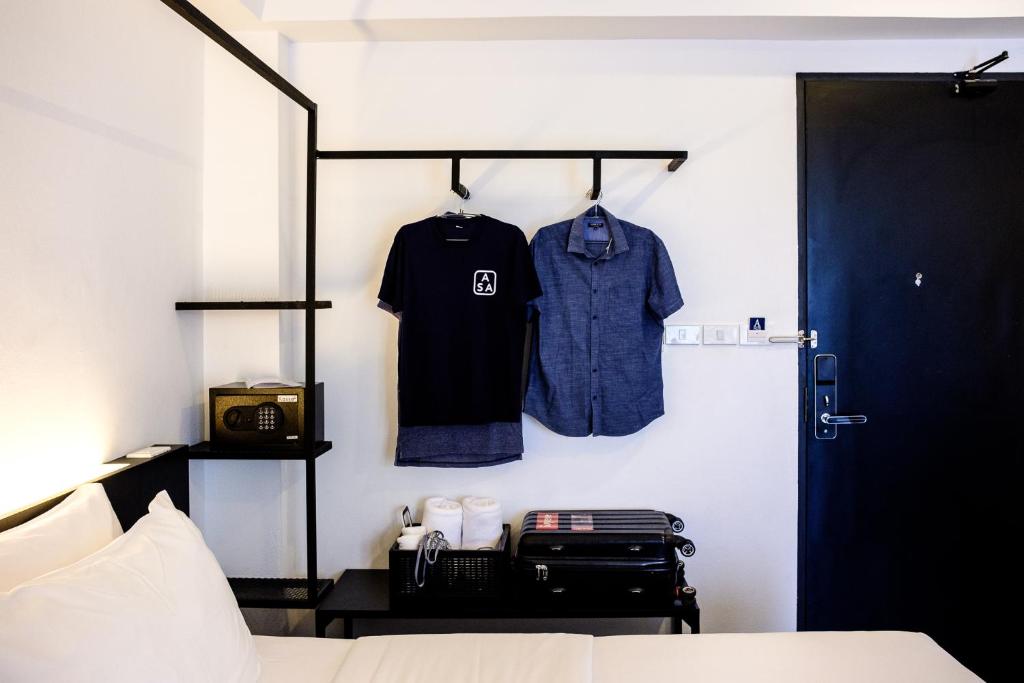 A bed-side view showing open clothes storage, a safe, drinks station, and the room door.