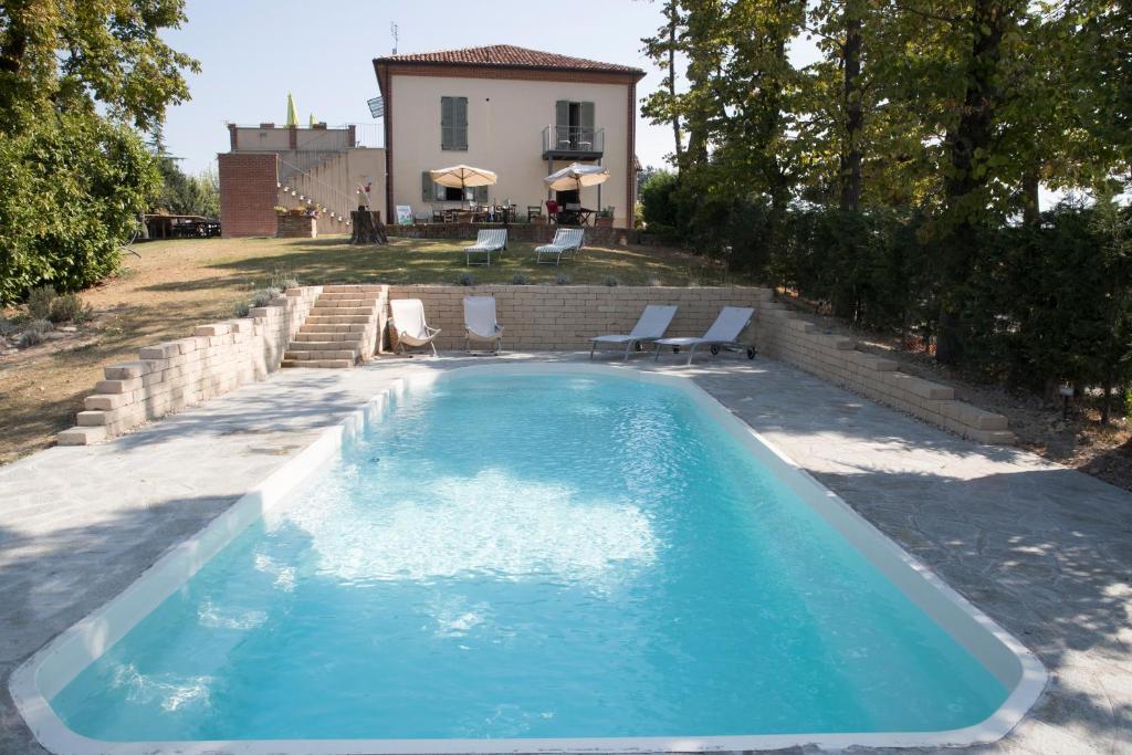 een zwembad met stoelen en een huis op de achtergrond bij Casa Vacanze San Stefanetto in Treiso
