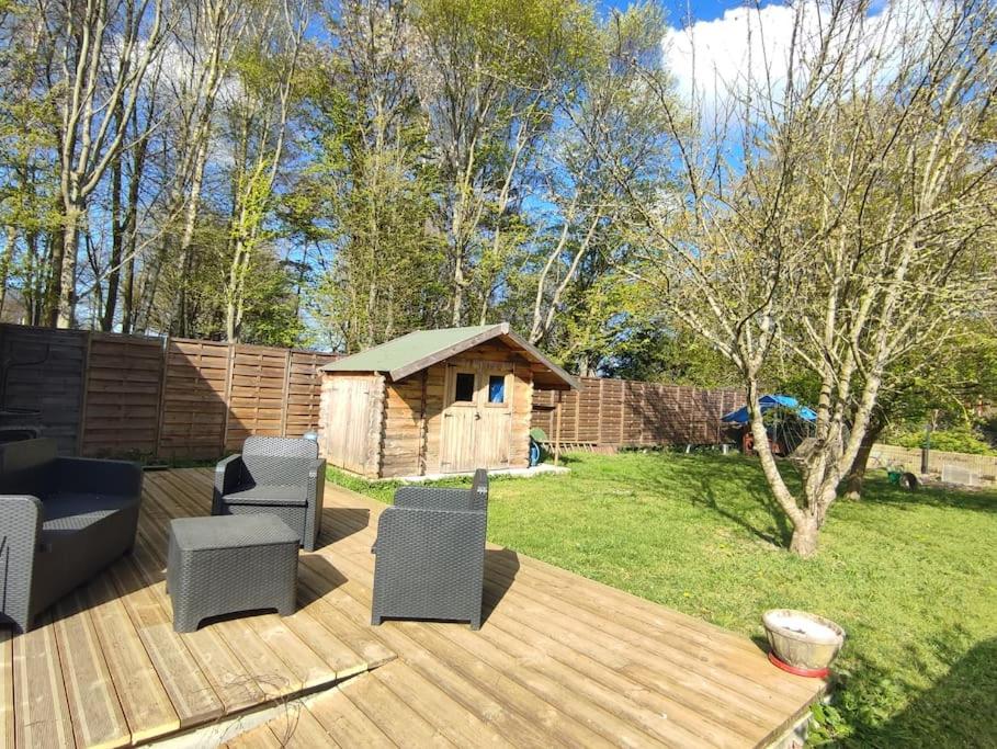 eine Holzterrasse mit Stühlen und ein Hundehaus in der Unterkunft Maison de ville ( à la campagne) in Bayeux