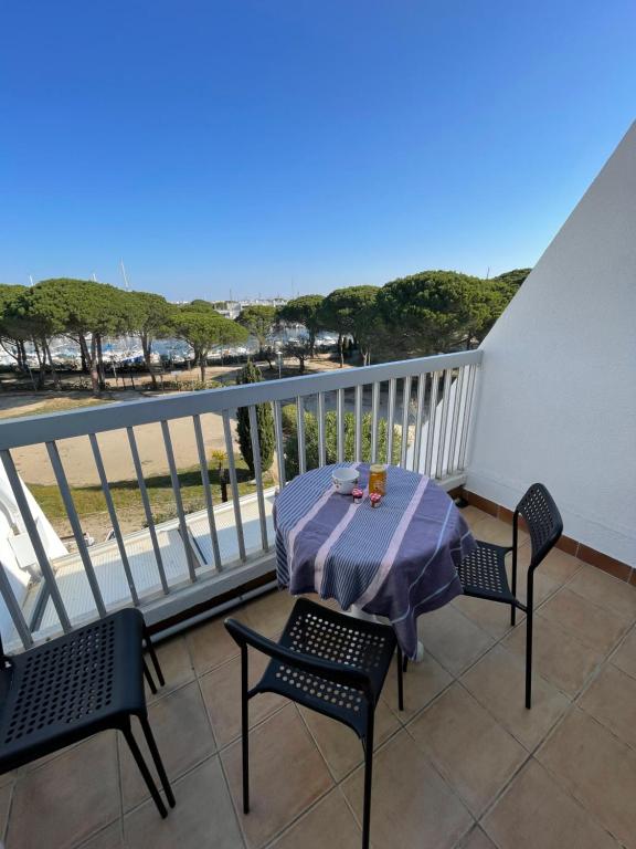 a table and chairs on a balcony with a view of the ocean at Studio vue port, parking privé, terrasse, clim in Le Grau-du-Roi