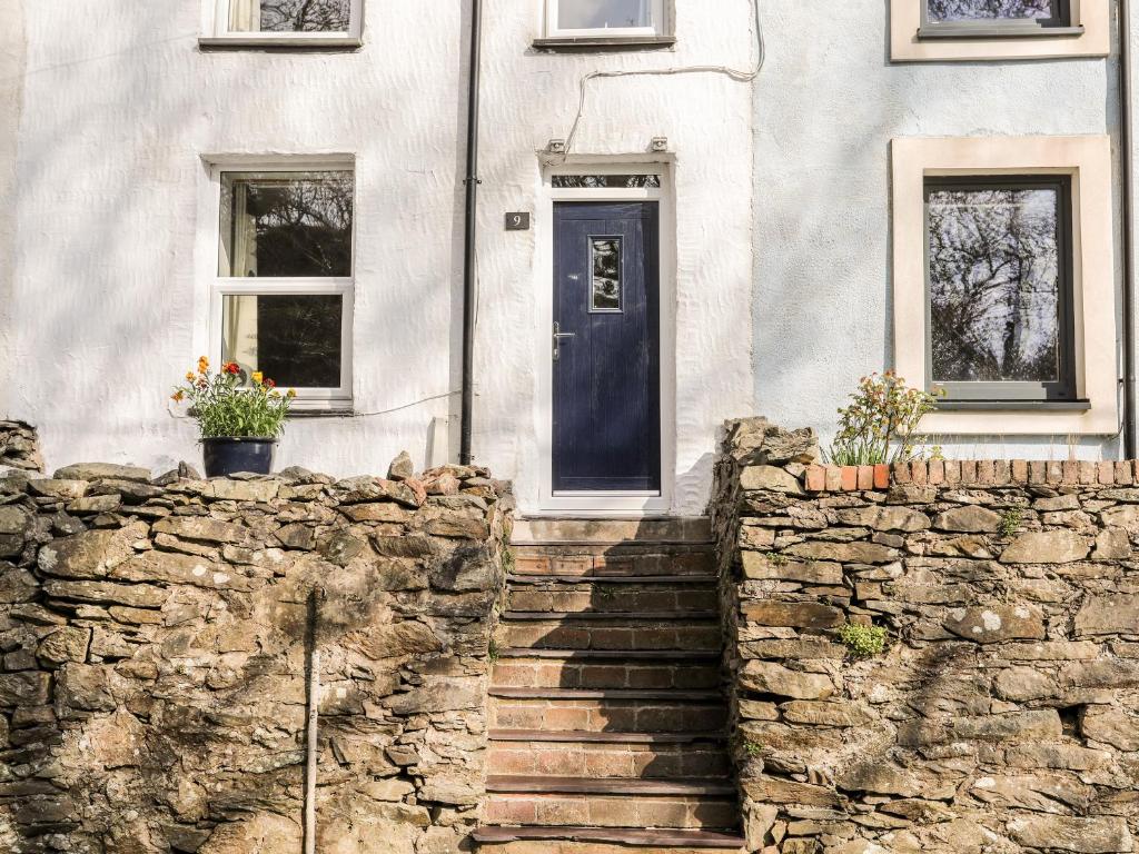 a house with a stone wall and a blue door at 9 Ty Du Road in Caernarfon
