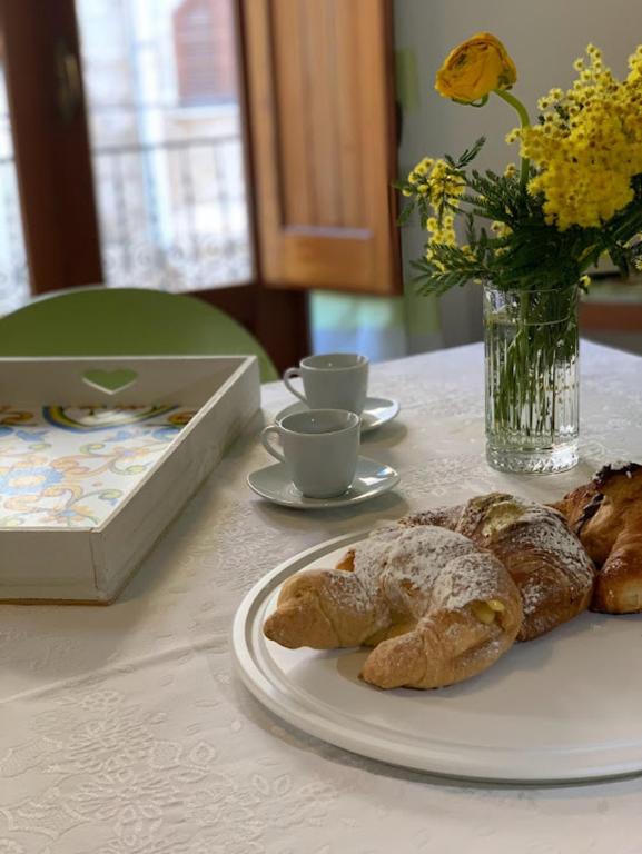 stół z talerzem wypieków i wazonem kwiatów w obiekcie Appartamento Casa Trento w mieście Castellammare del Golfo