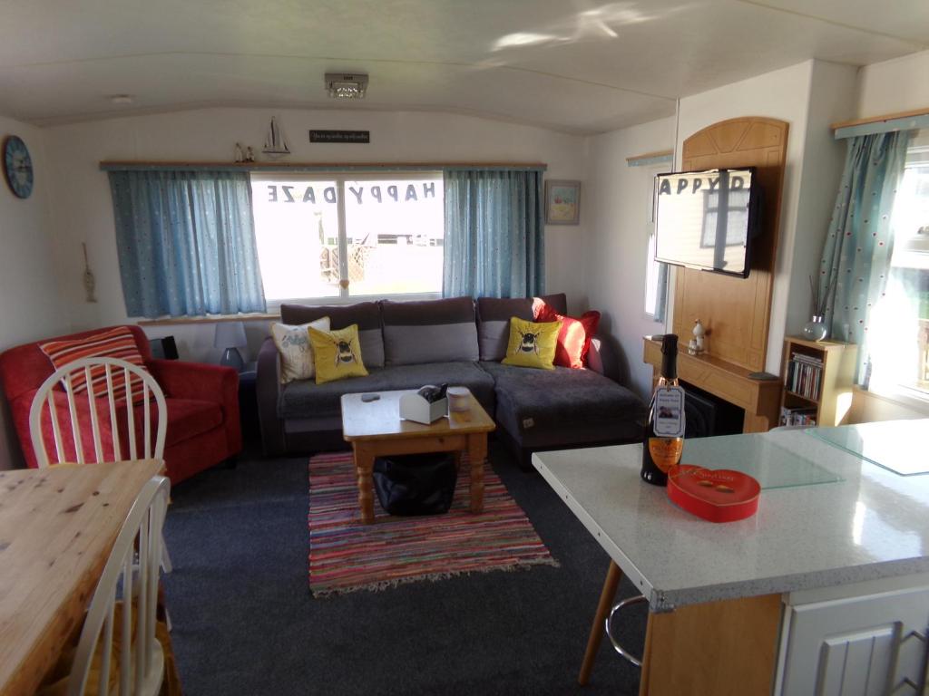 a living room with a couch and a table at Happydaze Caravan in Bacton