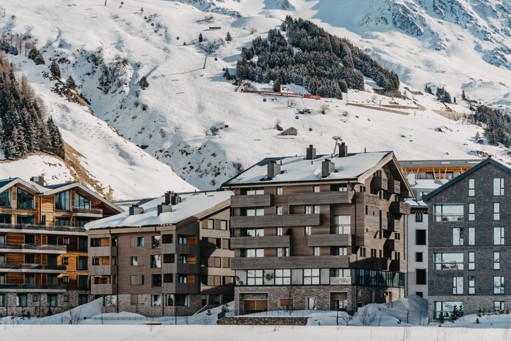 a building in front of a snow covered mountain at Andermatt Alpine Apartments in Andermatt