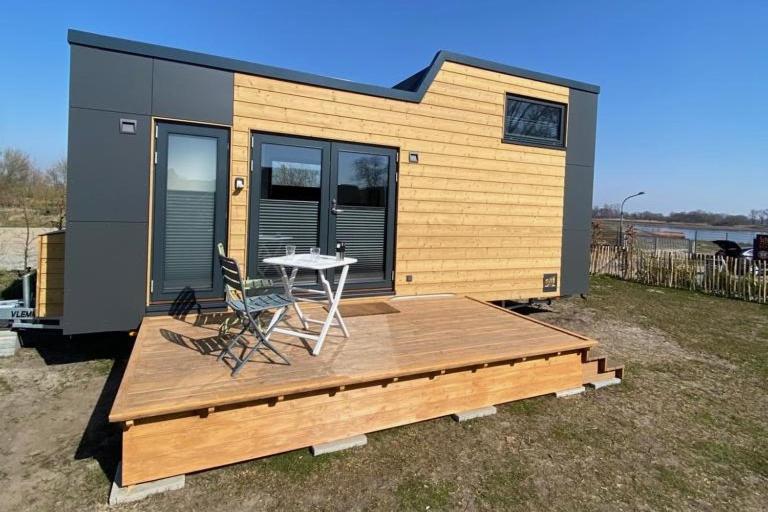 une petite maison avec une terrasse, une table et des chaises dans l'établissement Winzig Wohnen Tiny House Frigg direkt am Weserstrand, à Elsfleth