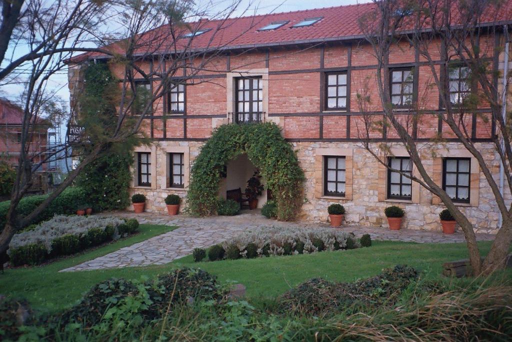 uma velha casa de tijolos com um arco num quintal em Posada Tresvalle em Ubiarco