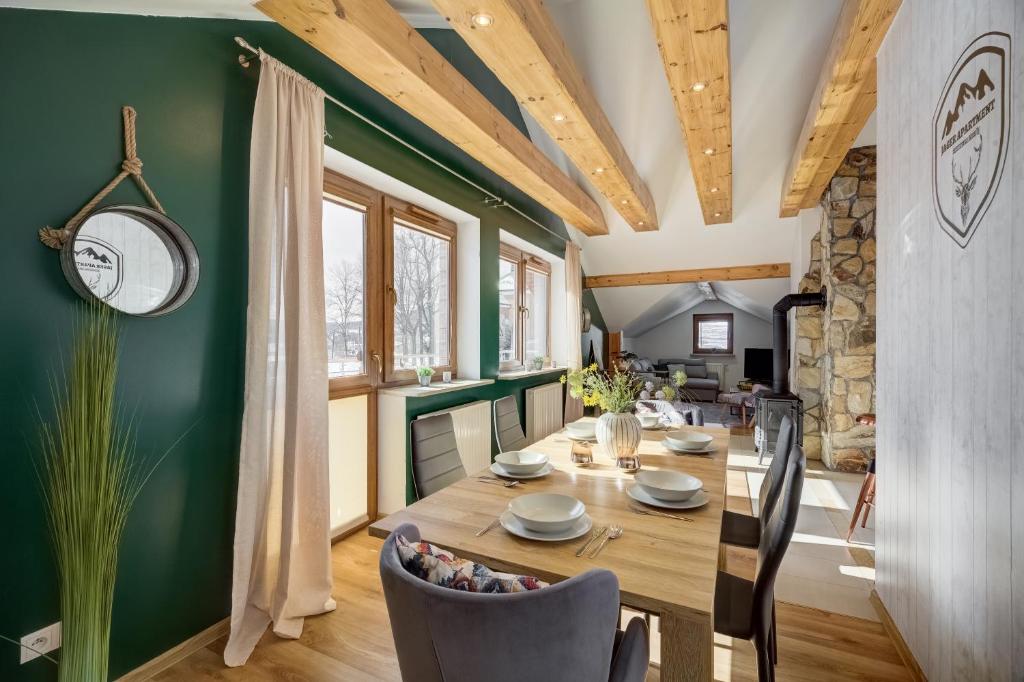 ein Esszimmer mit einem Holztisch und grünen Wänden in der Unterkunft Jager Apartment Krynica Zdrój in Krynica-Zdrój