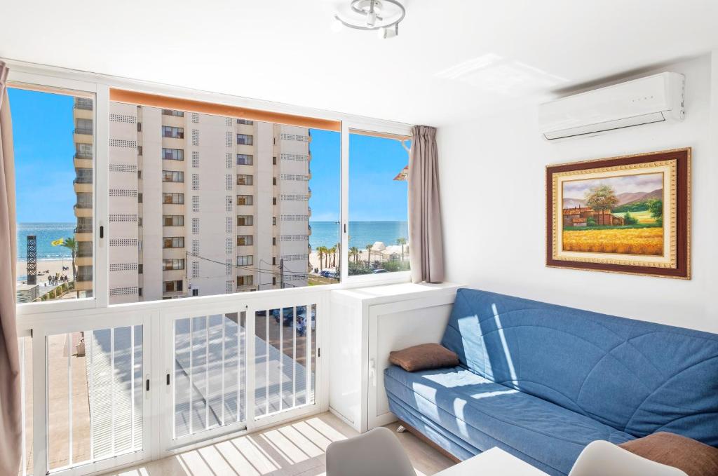 sala de estar con sofá azul y balcón en Bacana 3-3 Apartment Levante Beach, en Benidorm