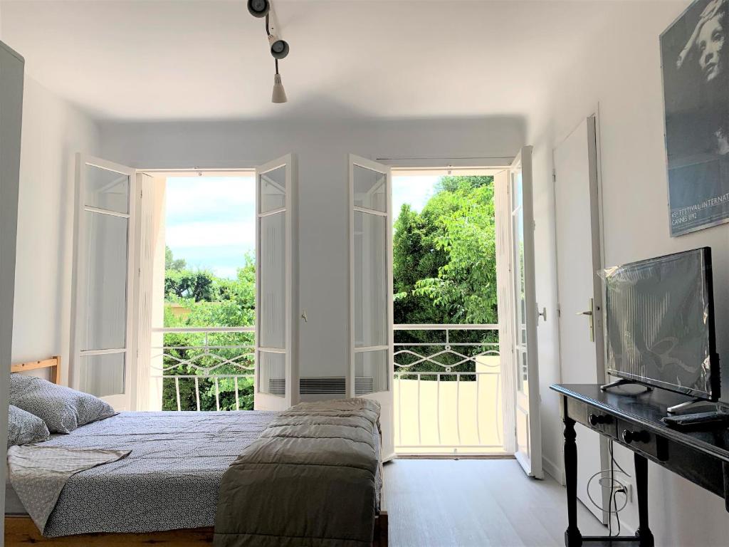 a bedroom with a bed and a large window at Cannes center parking very calm California neighborhood in Cannes