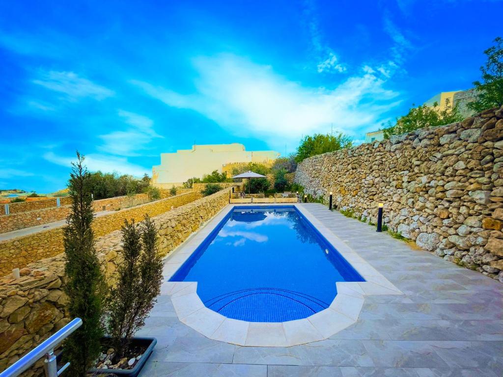 a swimming pool in a stone wall with a blue at Si-Ku Holiday Home with Private Pool and Hot Tub in Xagħra