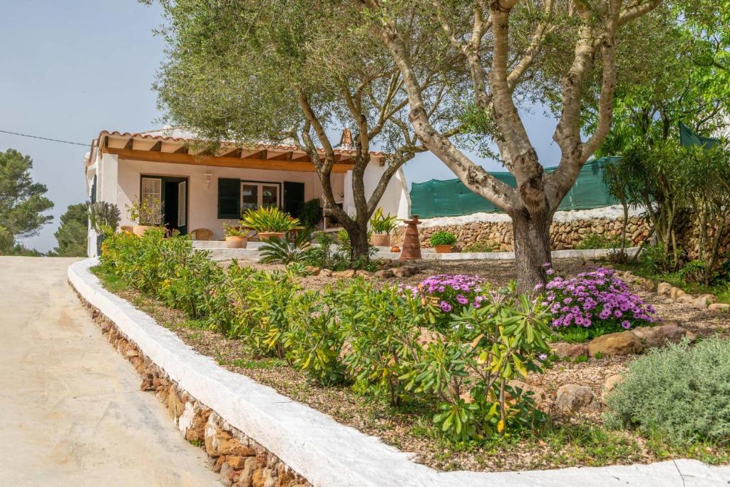 una casa con un jardín con flores y árboles en Casa Dina, en Es Mercadal