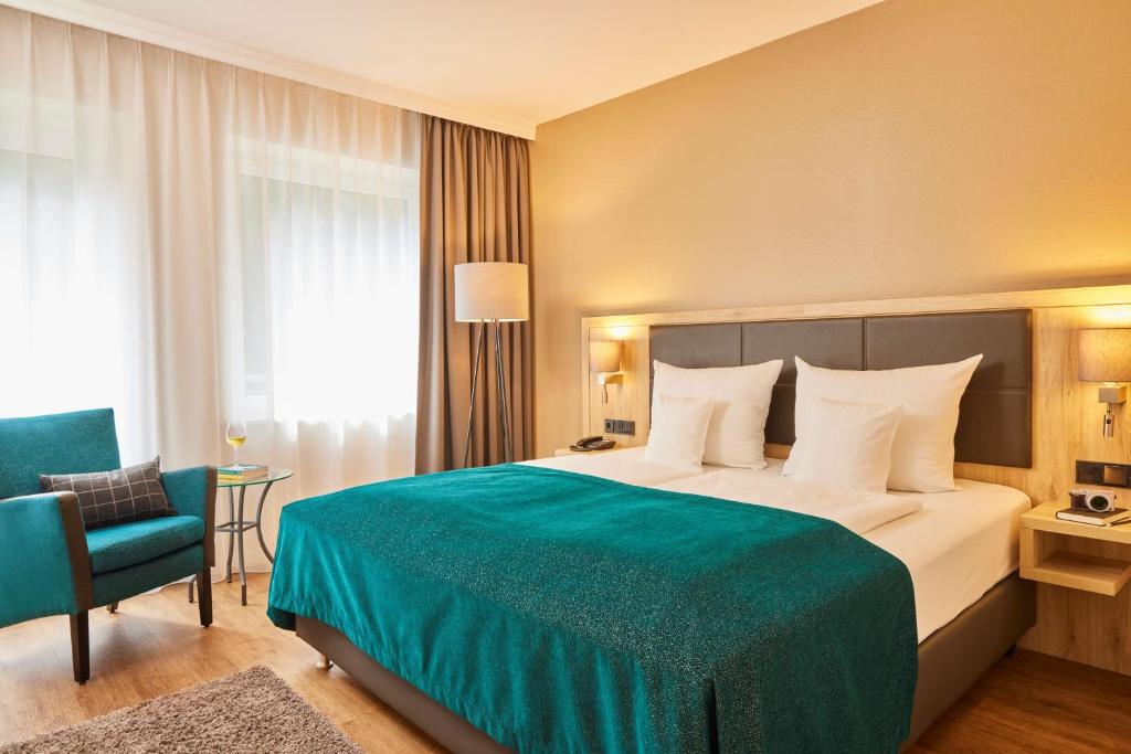 una habitación de hotel con una cama grande y una silla en Best Western Premier Alsterkrug Hotel en Hamburgo
