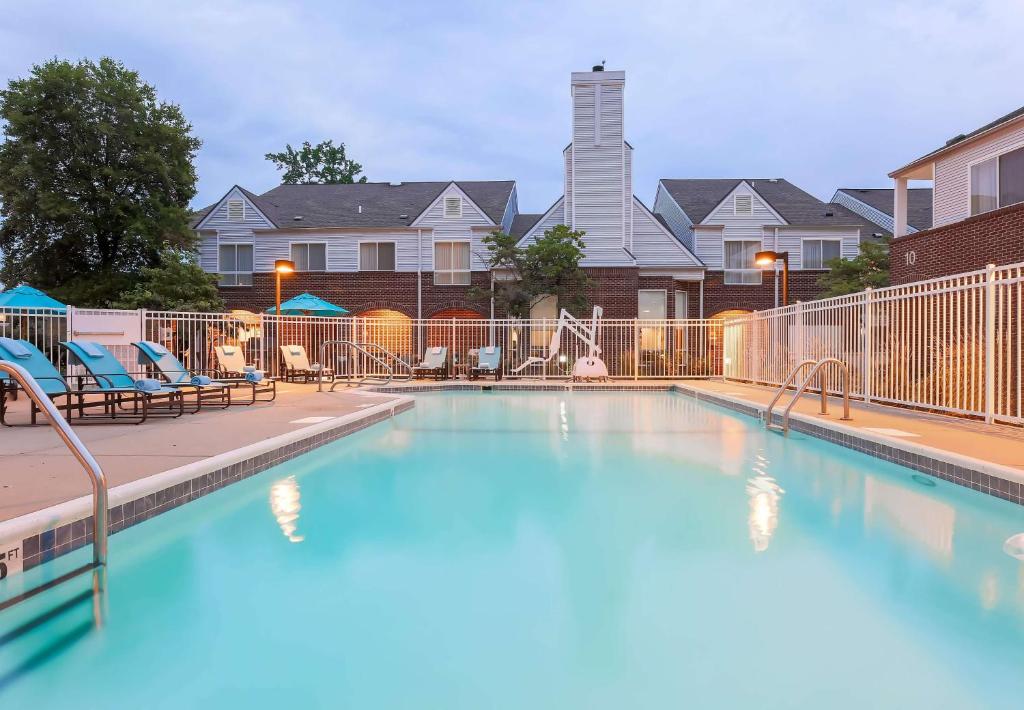 une grande piscine avec des chaises et une clôture dans l'établissement Sonesta ES Suites Cincinnati - Blue Ash, à Blue Ash