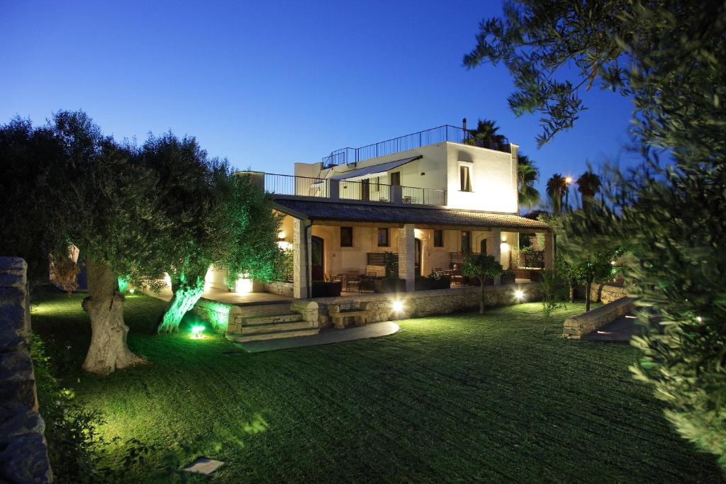 a large house with lights in a yard at night at Casal Sikelio in Cassibile
