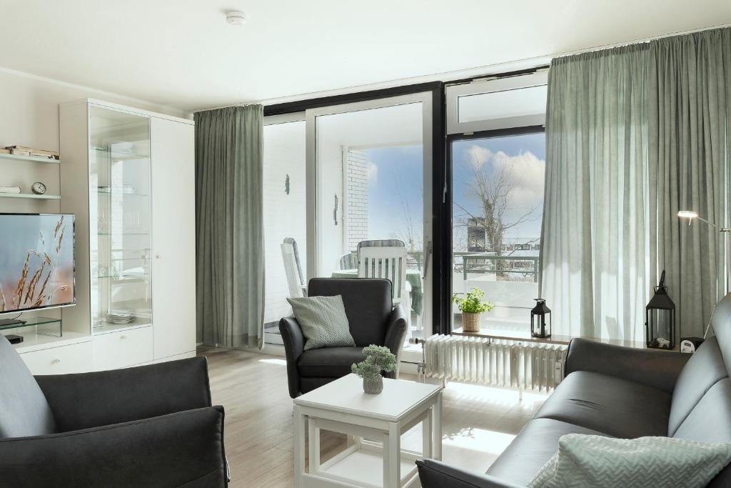 - un salon avec un canapé, des chaises et une télévision dans l'établissement Miramar Wohnung 509, à Grömitz