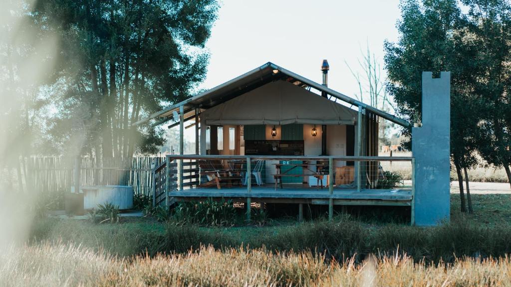 une petite maison avec une terrasse couverte dans un champ dans l'établissement AfriCamps at Oakhurst, à Wilderness