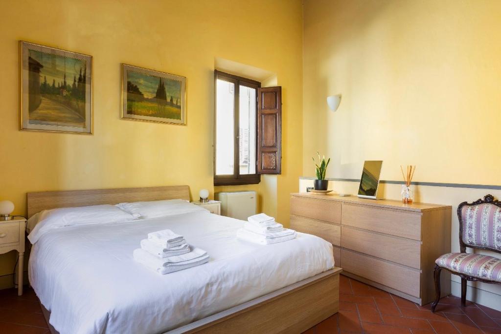 1 dormitorio con 1 cama blanca y 1 silla en Cozy classic Italian house near Santa Croce, on the Lungarno, en Florencia