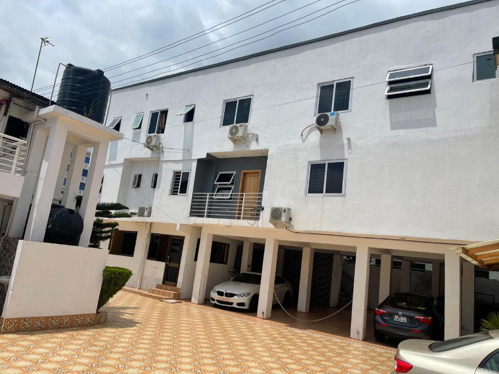 a white building with a car parked in front of it at Bonsukoda Lodge in Accra