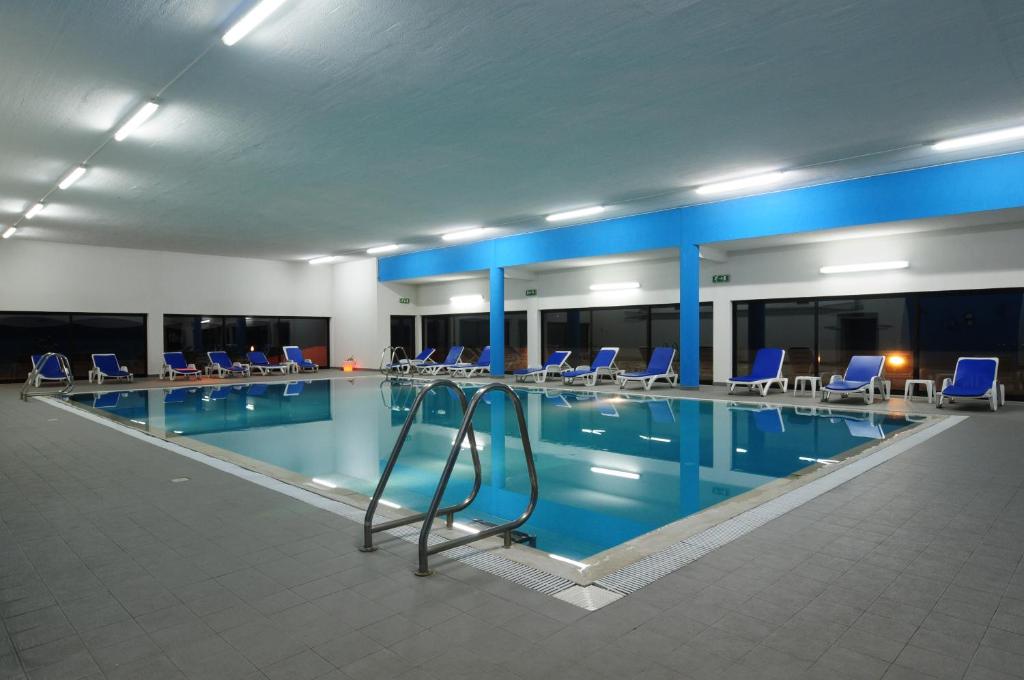 une grande piscine avec des chaises bleues dans un bâtiment dans l'établissement INATEL Piodao, à Piódão