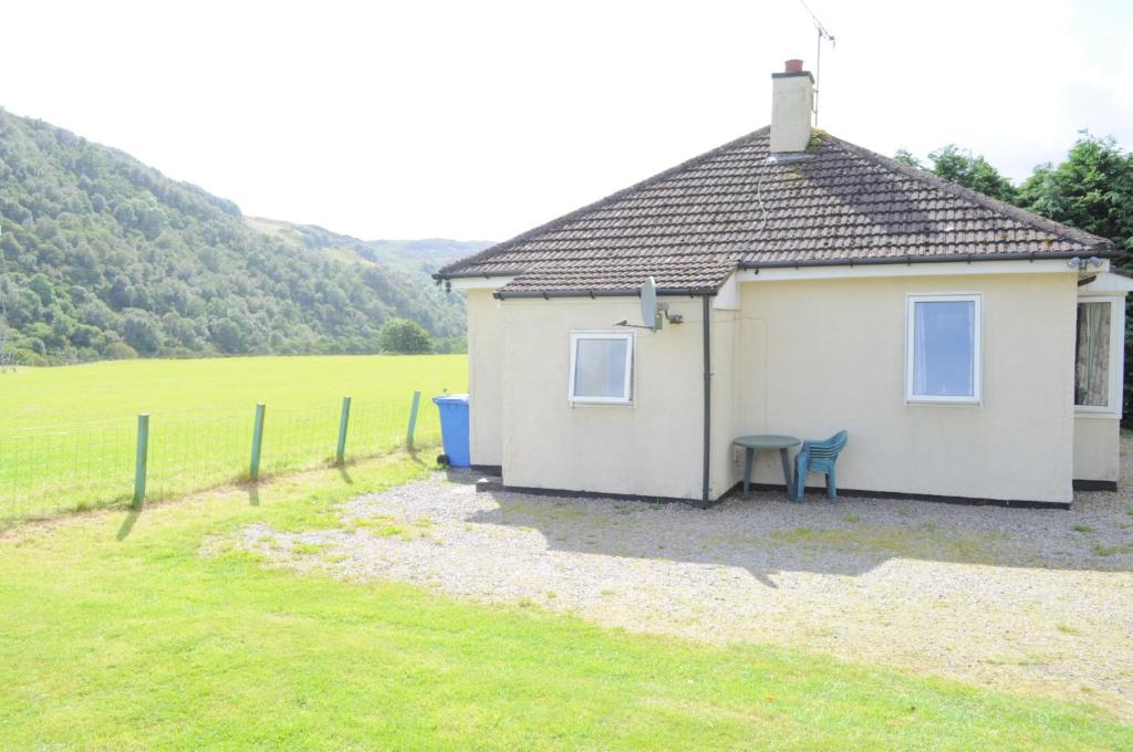 a small white house with a bench in a field at Lamont Chalets in Glenelg