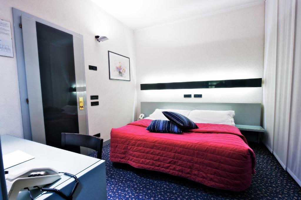 una camera d'albergo con un letto con una coperta rossa di Hotel Michelangelo a Biella