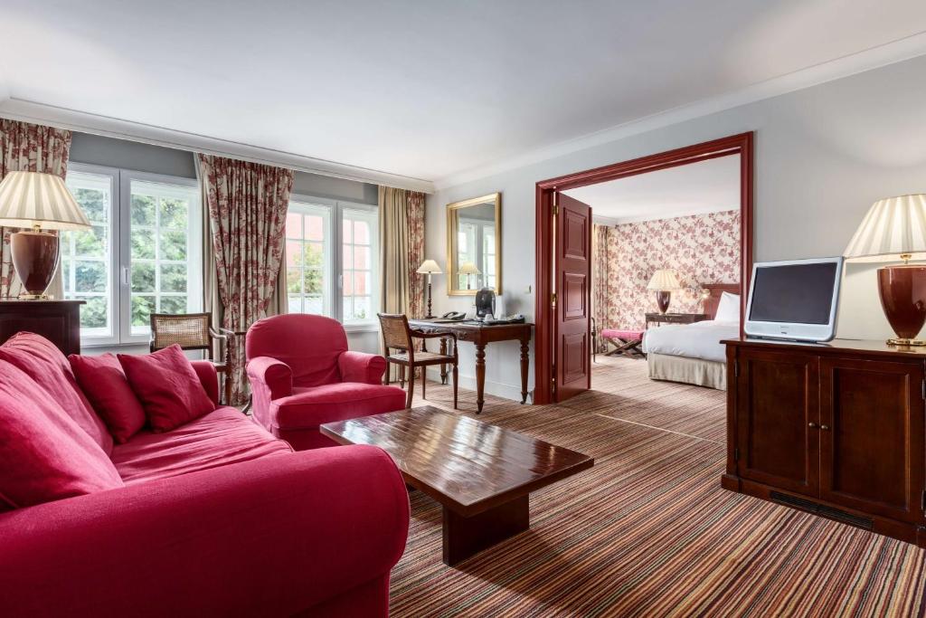 a living room with a red couch and a television at NH Brugge in Bruges