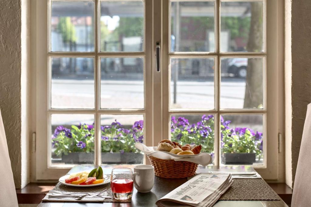 a table with a bowl of fruit and a window at NH Brugge in Bruges