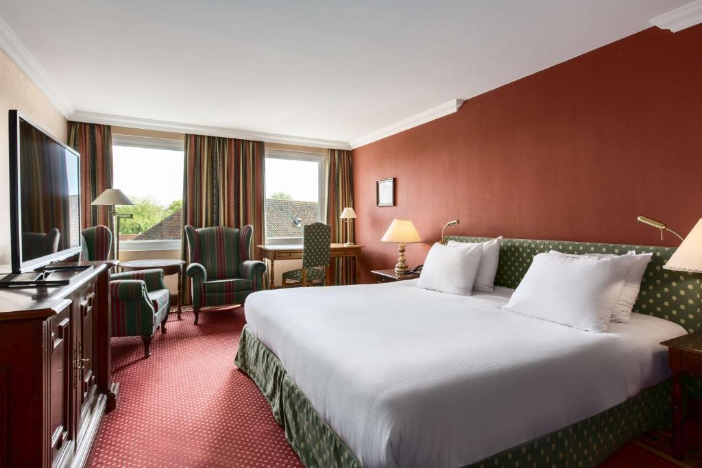 a hotel room with a large bed and a television at NH Brugge in Bruges