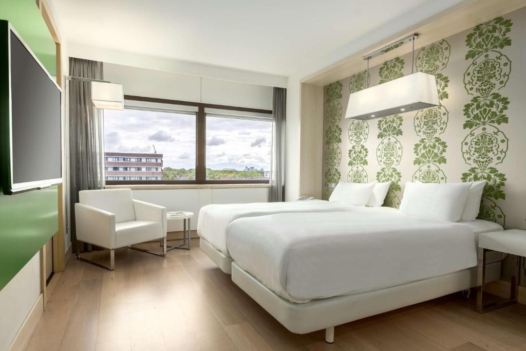 een slaapkamer met een groot wit bed en een raam bij NH Amsterdam Zuid in Amsterdam