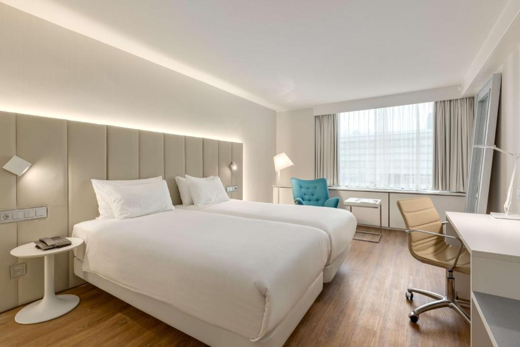 Habitación de hotel con cama blanca grande y escritorio. en NH Utrecht en Utrecht