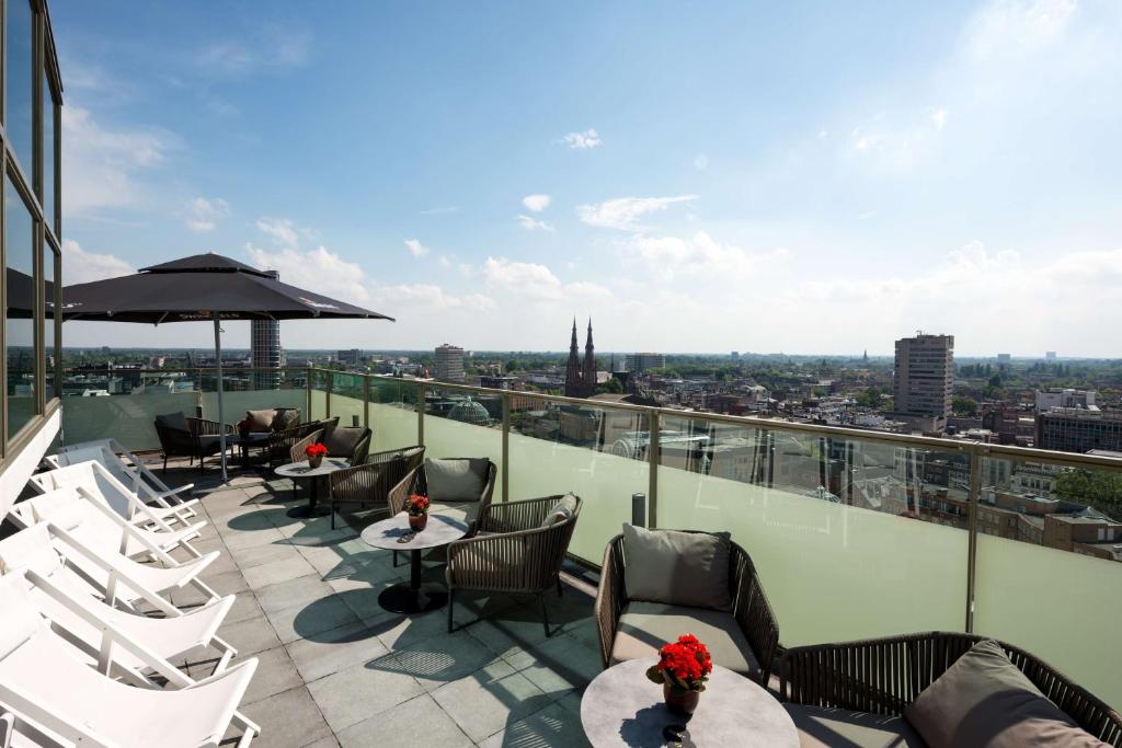 een patio met stoelen en tafels bovenop een gebouw bij NH Collection Eindhoven Centre in Eindhoven