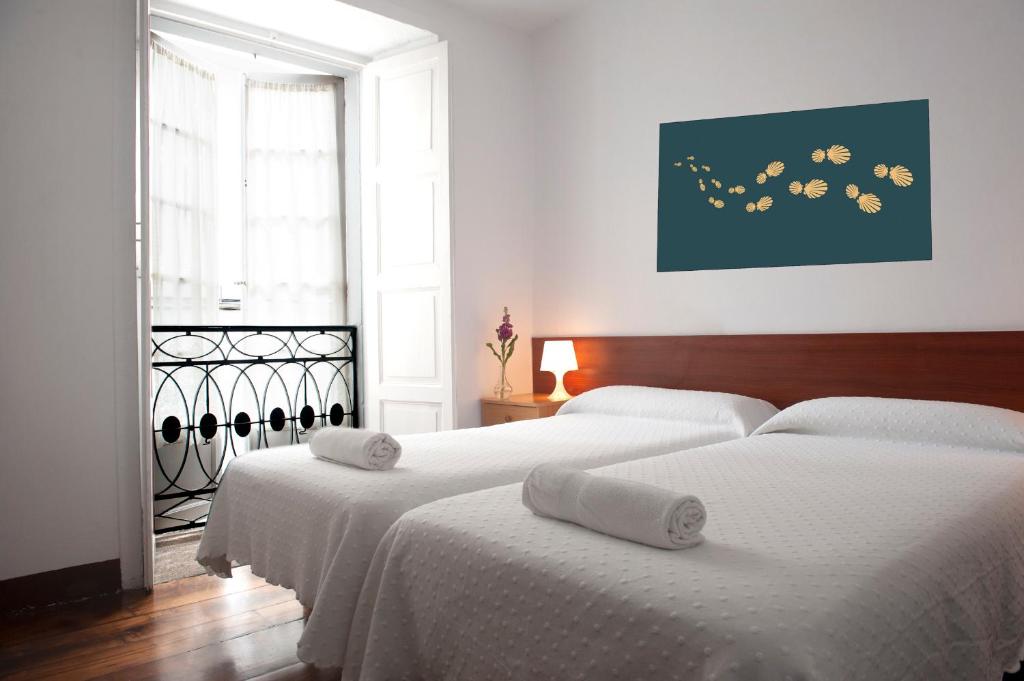 1 dormitorio con 2 camas con sábanas blancas en Pensión Santa Cristina, en Santiago de Compostela