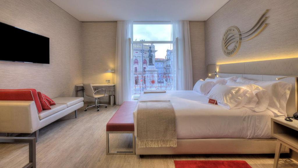 a hotel room with a large bed and a window at NH Collection Porto Batalha in Porto