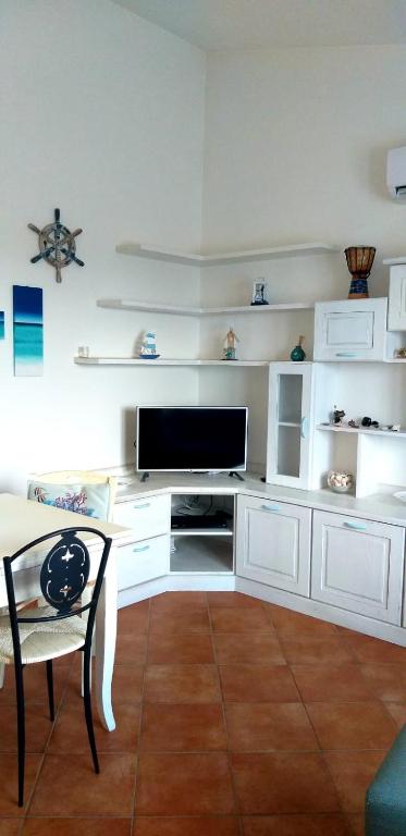 a living room with a tv and a chair and shelves at Casetta Francy in San Teodoro
