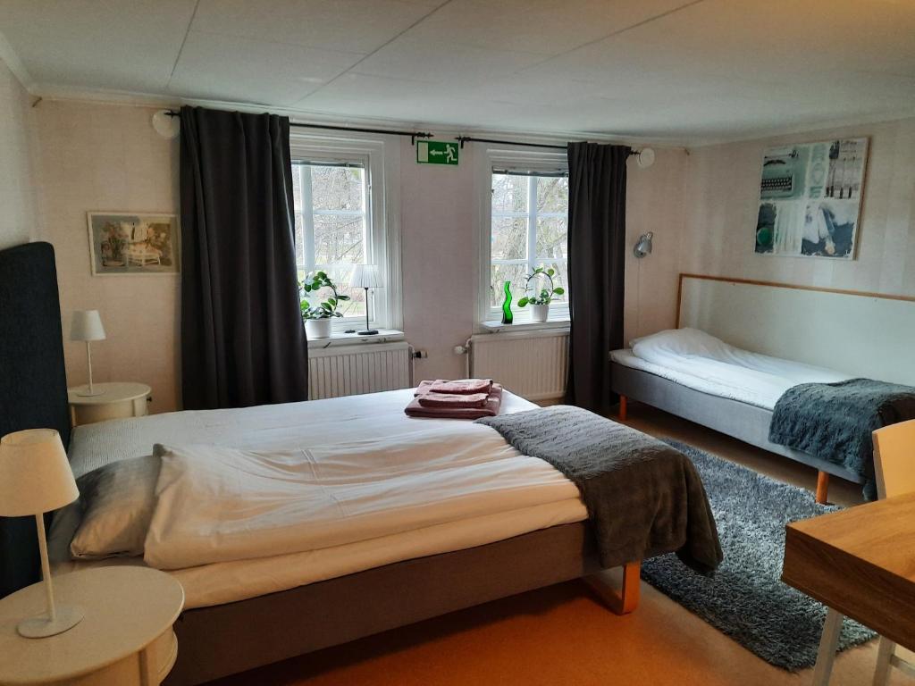 1 dormitorio con 2 camas y 2 ventanas en KvarnDammens Bed & Breakfast en Vetlanda