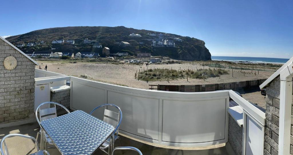 a blue table and chairs on a balcony with a beach at Whispering Waves in Porthtowan @ Cornwall Coastal Holidays in Porthtowan