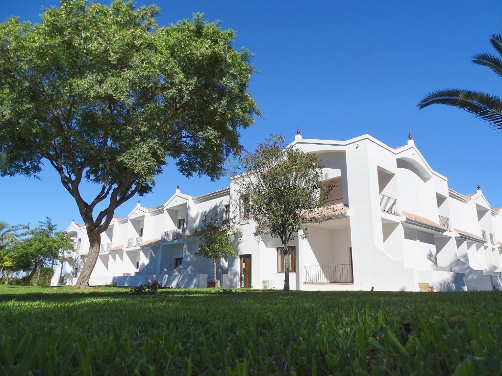 un grande edificio bianco con un albero di fronte di Hotel La Parra a Jerez de la Frontera
