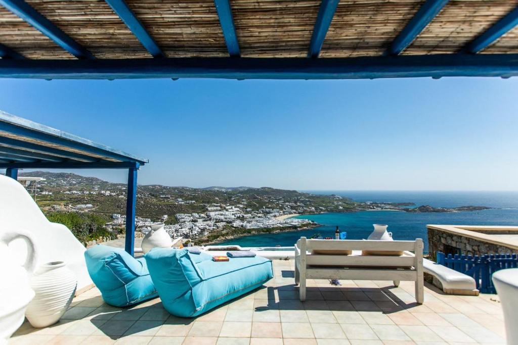 patio con mobili blu e vista sull'oceano di Mykonos Coastal Retreat - Giovanna's Beachfront Escape with Jacuzzi a Mykonos Città