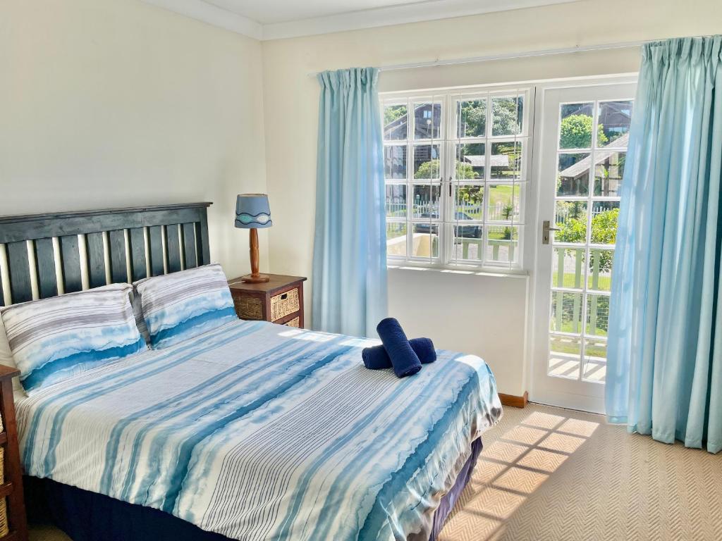 a bedroom with a large bed with blue curtains at 59 Settler Sands Beachfront Accommodation in Port Alfred