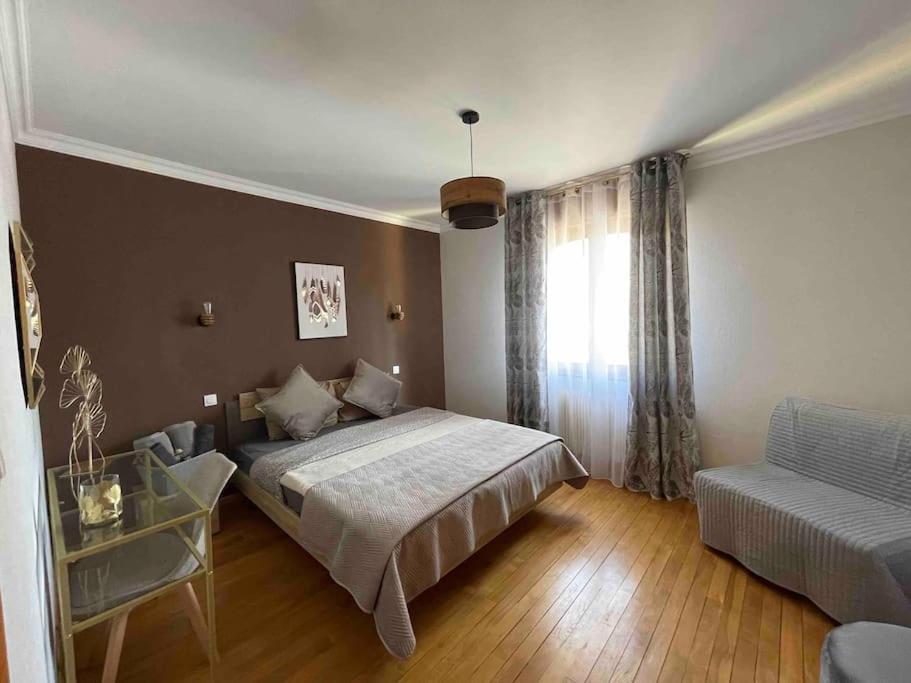 a bedroom with a bed and a couch and a window at EVASION gîtes et spa in Saint-Léonard