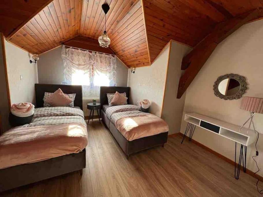 a bedroom with two beds and a wooden ceiling at EVASION gîtes et spa in Saint-Léonard
